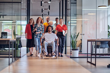 Naklejka na ściany i meble A diverse group of young business people congregates within a modern startup's glass-enclosed office, featuring inclusivity with a person in a wheelchair, an African American young man , and a hijab