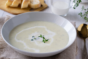Zucchini and potato cream soup on wooden table with thyme