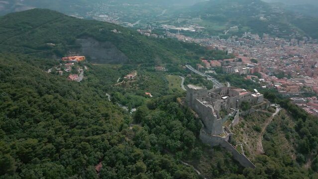 Drone shot over Arechi Castle on a green forested hill