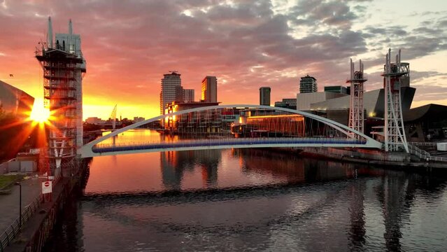 Golden sunset over a Salford Quays foot bridge, people passing by over the bridge. 