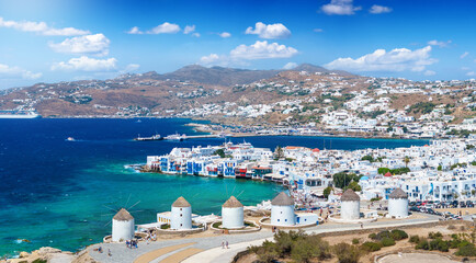 Aerial view through the famous windmills above Mykonos town, Cyclades, Greece, to the Little Venice district during summer time - obrazy, fototapety, plakaty