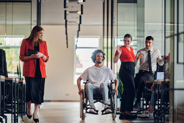 Fototapeta na wymiar A group of young business people in a modern glass-walled office captures the essence of diversity and collaboration, while two colleagues, including an African American businessman in a wheelchair