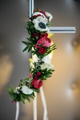 a cross decorated with flowers sitting inside of a room next to a wall