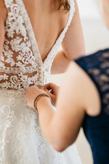 a bride looking at the back of her wedding dress, putting on rings