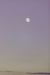 moon in purple skies with low clouds in the foreground