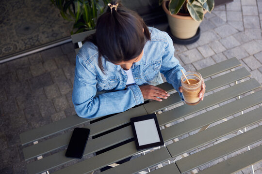 Woman in cafe reading book on ebook reader with blank empty screen