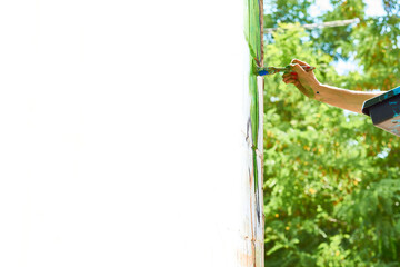 Female artist's hand with a brush painting on the wall,place for text