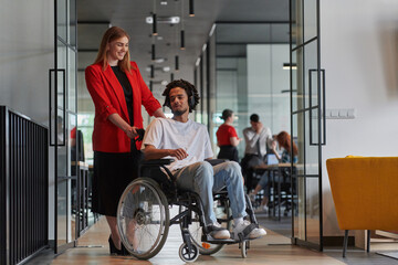 A group of young business people in a modern glass-walled office captures the essence of diversity and collaboration, while two colleagues, including an African American businessman in a wheelchair