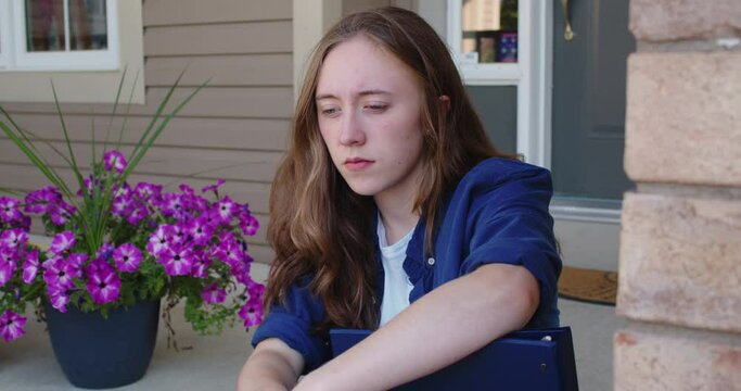 Sad Student Sitting on Steps Outside of a Suburban House