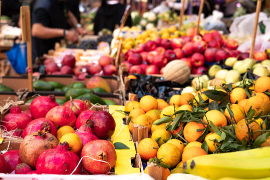 Fruit and vegetable stall in a street market in Naples in Italy. Signs with prices in the background, oranges, bananas, pomegranates.