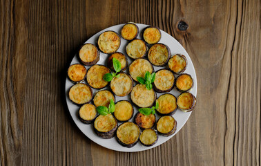 Fried eggplant on a white plate, garnished with basil leaves