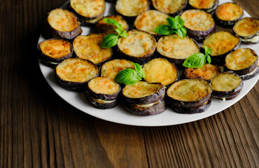Fried eggplant on a white plate, garnished with basil leaves