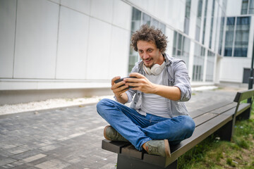 man use mobile smart phone play video games sit outdoor