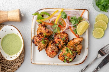 Plate of Indian cuisine featuring tandoori chicken, garnished with fragrant onions