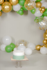 Cake with white cream, decorated with gold confectionery sprinkles on a white background. Two-tiered white wedding cake.