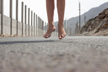 Pies descalzos de una niña saltando en el medio de la pista en un día soleado.