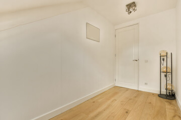 an empty room with white walls and wood flooring on the right side, there is a lamp in the corner
