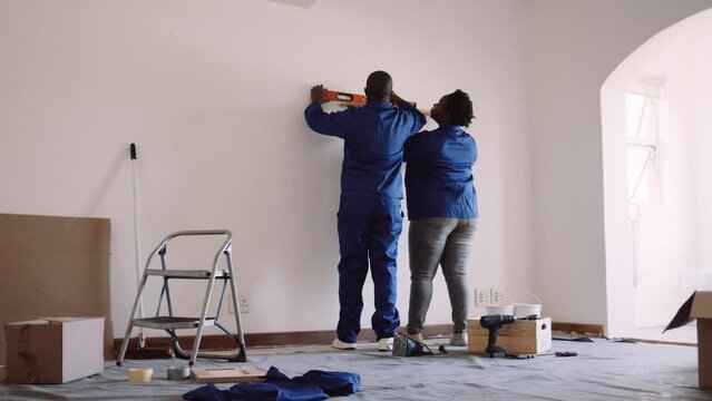 Black couple measuring and levelling shelf in DIY renovation