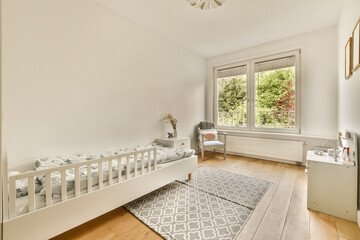 a baby's room with white walls and hardwood flooring there is a cribe bed in the corner