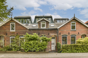 a house in the netherlands with an orange brick facade and green plants growing on the front yard, surrounded by trees
