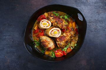 Traditional slow cooked German pork roulades with vegetable and bacon served in spicy gravy sauce as top view in a design pot with copy space