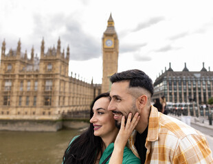Fototapeta na wymiar pretty tourist couple taking photo in london - multiracial couple selfie -