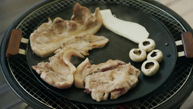 Closeup of meat steaks and stuffed mushrooms on metal grill