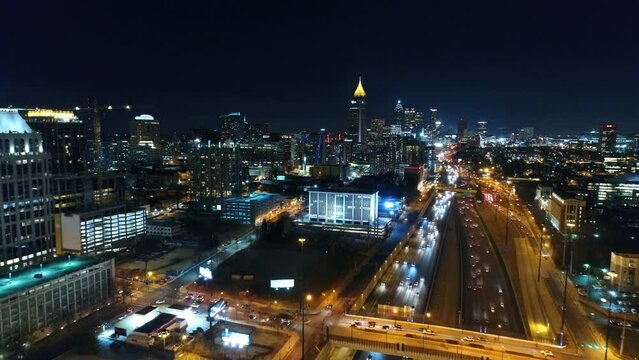 Aerial Shot Of Illuminated Modern Buildings By Roads In City, Drone Flying Backward Over Vehicles - Atlanta, Georgia