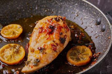 Lemon and honey pan cooked chicken breast with onions herbs and garlic,resting in the pan with the juices.
