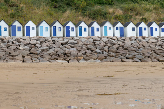line of white wooden bath houses on a beach