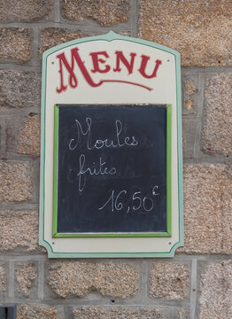 menu outdoors on a wall from a restaurant written "moules frites" on it (means: shells fries)