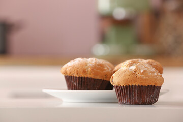 Plate with delicious muffins on table in kitchen