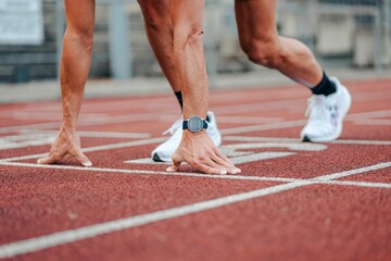 Closeup of a male athlete wearing a sport watch, ready to start a race