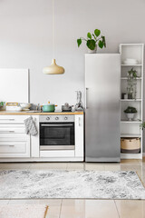 Interior of light kitchen with stylish fridge, counters and shelving unit