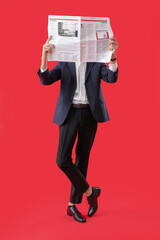 Young man in suit reading newspaper on red background