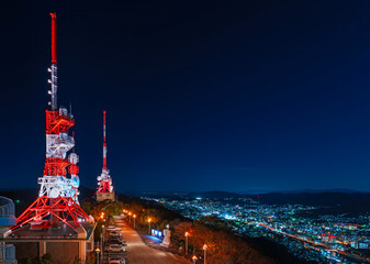 kyushu, nagasaki - dec 12 2022: Night cityscape praised for its 10-million-dollar night view from the observation deck of mount Inasa overlooked by two Digital Television Transmitting Station antennas