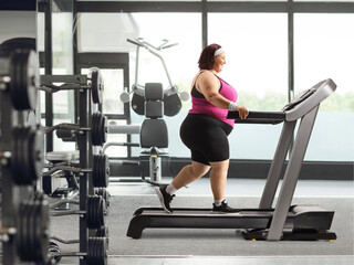 Overweight woman walking on a treadmill at a gym