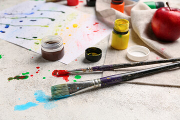 Jar of paints and brushes on light grunge table