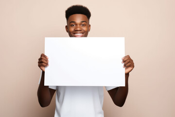 Young smiling african american man holding white empty paper sheet with space for text.