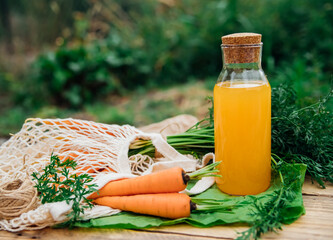 Fresh carrots on a wooden background. Food for vegetarians. Homemade vegetables, eco-friendly, healthy food. Glass jug with carrot juice on a wooden table.