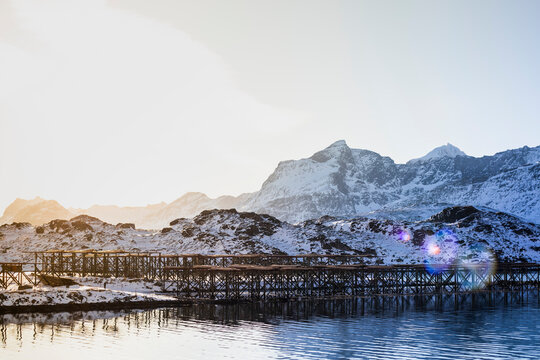 Snowy mountains near sea with cod plantations in sunshine