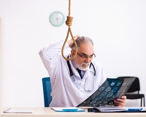 Old male doctor committing suicide at workplace