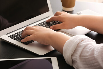 Female programmer typing on laptop keyboard at her workplace in office, closeup