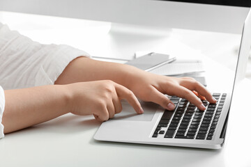 Female programmer typing on laptop keyboard at her workplace in office, closeup