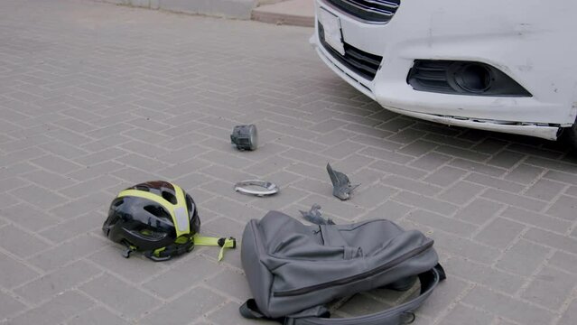 The scene of a road accident between a car and an electric scooter. Footage of a schoolboy hit by a car and his helmet and schoolbag falling to the pavement at an intersection near the school.