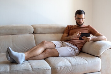 Young male model reading kindle and lounging on the sofa 