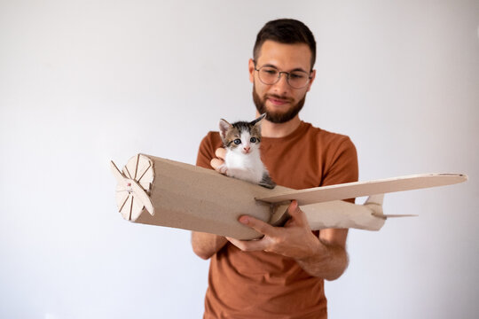 Young male model playing with the kitten in handmade toy airoplane.