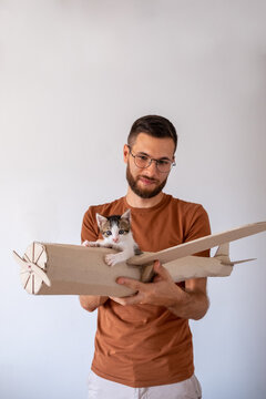Young male model playing with the kitten in handmade toy airoplane.