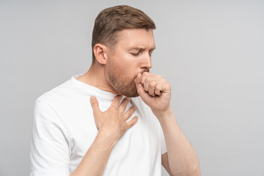 Portrait of sick man suffers bad cough, sore throat, chest pain on grey background. Health problem bronchitis cough seasonal cold, tracheitis, illness concept. Banner poster for medical advertisement.