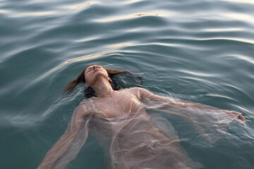 relaxation, woman floating in water with closed eyes